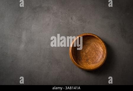 Top view of empty wooden nuts bowl on dark grey stone table Stock Photo