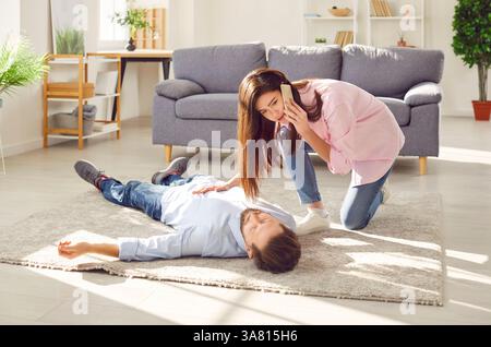 Woman calls 911 to help man who is having heart attack and lying unconscious on floor Stock Photo