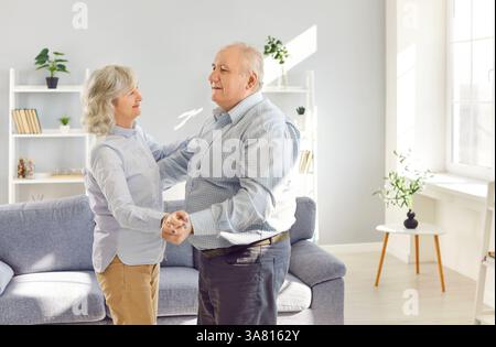 Happy active old retired senior couple dancing close in modern living room, loving middle aged  Stock Photo