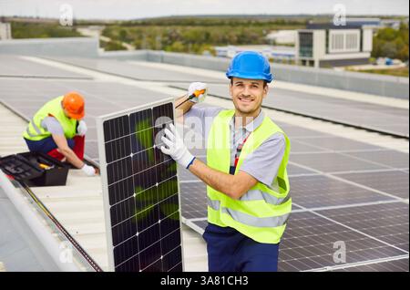 Two men are working on installing solar panels on the roof of a building. Stock Photo
