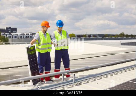 Technicians Installing Or Maintaining Solar Panels With Laptop On Roof Stock Photo