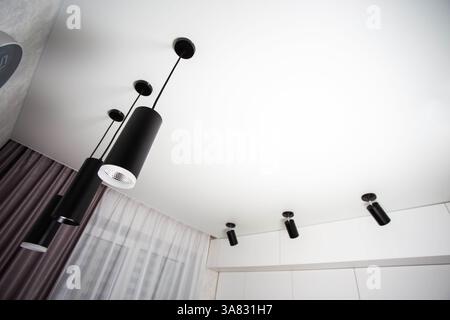 Modern suspended ceiling with different black LED lamps on a white ceiling in the kitchen. Copy space for text Stock Photo