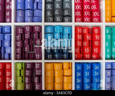 Close-up of a white plastic section tray filled with colourful size markers for clothes hangers, neatly organised by size for retail use Stock Photo