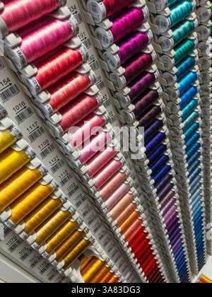 Reels of colourful Gütermann cotton thread neatly arranged and sorted by colour in a shop display rack Stock Photo