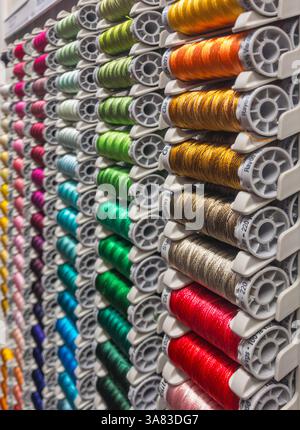 Reels of colourful Gütermann cotton thread neatly arranged and sorted by colour in a shop display rack Stock Photo