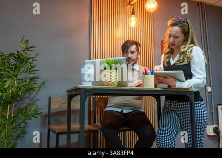 Coworkers collaborating on a project using a laptop in an office Stock Photo