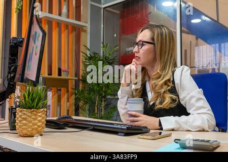 Businesswoman working on computer in office analyzing charts Stock Photo