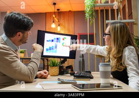 Businesswoman pointing at graphs on computer screen Stock Photo