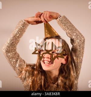 girls celebrating New Years eve with a sparkly dress and star glasses Stock Photo
