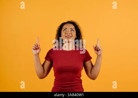 Young African American woman pointing upward at copy space with both hands Stock Photo