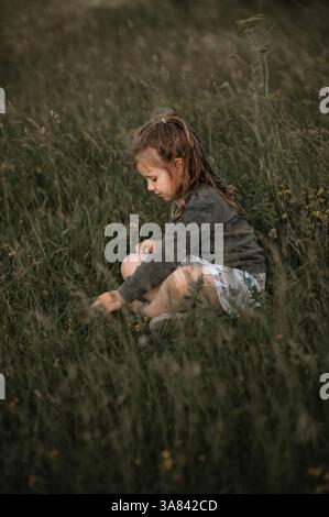Cheerful girl sitting on grass with red and white balloons in mid-air ...