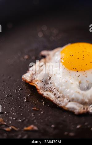 Close up of sunny-side up egg cooking in a black frying pan. Stock Photo