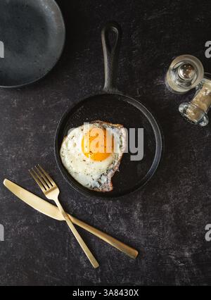 Top view fried egg in pan with plate cutlery on black background. Stock Photo
