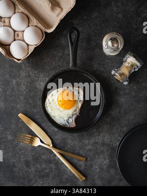 Top view fried egg in pan with plate cutlery on black background. Stock Photo