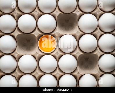 Top view of carton of white eggs with three missing and one broken. Stock Photo