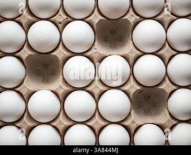 Top view of carton of 30 white eggs with three missing. Stock Photo