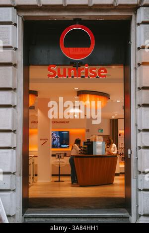 21-03-2023 Zurich, Switzerland.Sunrise store entrance door with staff and customers inside. Late evening, outside looking in shot Stock Photo