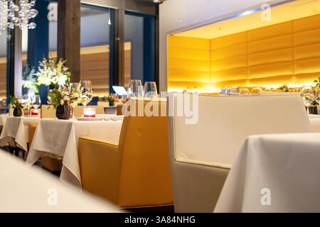 Empty set tables and benches inside fancy restaurant in the evening before start of service, Selective focus, shallow depth of field, interior lightin Stock Photo