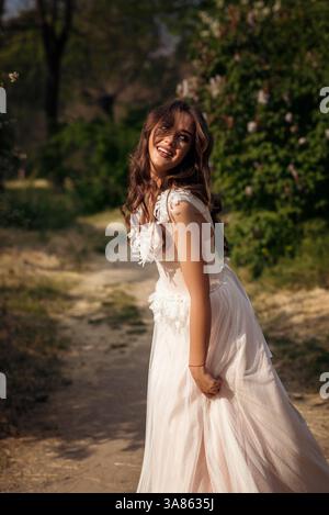 Stunning bride gracefully poses in a spring park, among blossoming trees. exuding elegance, Stock Photo