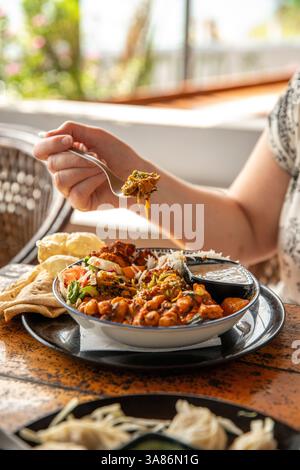 Woman eating a Buddha Bowl, Varkala Beach, Kerala, India Stock Photo