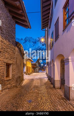 View of town centre and snow covered mountains in background at dusk, Courmayeur, Aosta Valley, Italian Alps, Italy Stock Photo