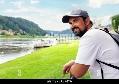 Portrait young adult happy man portrait enjoy tourism trip Sachsische Schweiz National Park Germany Whelen Koenigstein mountain valley blue sky sunny Stock Photo