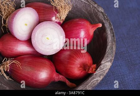 Close up of Tropea red onions on a wooden bowl and a sliced red onion on top. Stock Photo