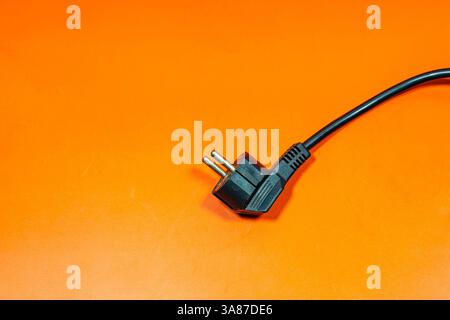 Black plug cable on an orange surface. Stock Photo