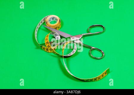 Tape measure and sharp tailor's scissors, placed on the table. Stock Photo