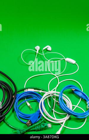 Wired headphones and many colorful cables on a green surface Stock Photo
