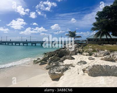 Oistins jetty along with rocks and palm trees as seen from Oistins Beach, Barbados on a beautiful sunny day. Stock Photo