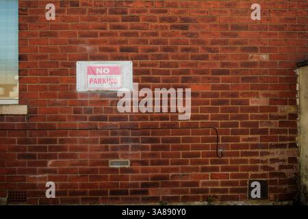 Faded no parking sign on a brick wall Stock Photo