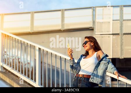 Smiling urban woman standing on city stairway checking smartphone Stock Photo