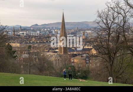 Young couple walking their dog in Queens Park, Looking north across the city centre of Glasgow, Scotland towards the Campsie Hills, Govanhill, Glasgow Stock Photo