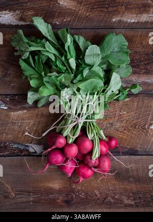 A bunch of fresh red radishes on top of rustic wooden table Stock Photo