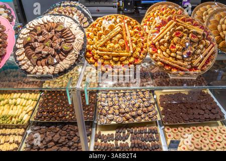 A display case with pastries, sweets and cookies, chocolate coated treats, candies, assorted cookies, and baked goods in arrangement in Saudi Arabia Stock Photo