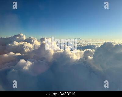 View of fluffy clouds from above during a clear sky at sunset Stock Photo
