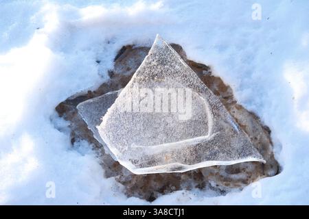 Top down view of transparent ice floe melting on coast of Baltic sea, close-up. Change of seasons, winter and spring. Sandy melting spot under ice Stock Photo