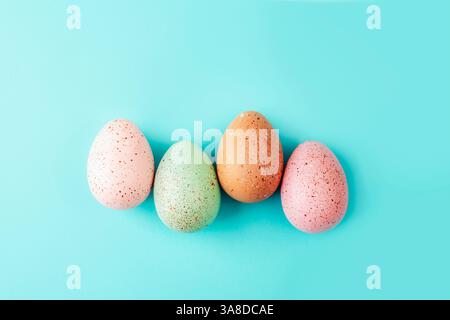 Speckled pastel Easter eggs on turquoise background. Top view, flat lay. Stock Photo
