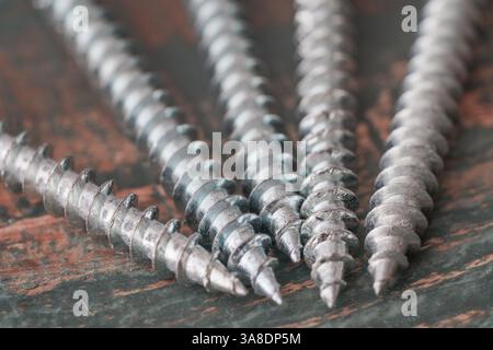Close-up of metal screws on a rustic wooden surface, perfect for construction, repair, and home improvement projects. Stock Photo