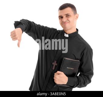 Young priest with Holy Bible showing thumb-down on white background Stock Photo