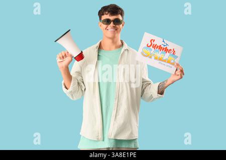 Handsome young man holding paper with text SUMMER SALE and megaphone on blue background Stock Photo