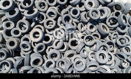 A pile of old tires with a lot of different sizes. The tires are all different colors and sizes, and they are piled on top of each other. Concept of w Stock Photo