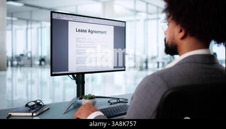 African American man examines lease agreement on digital desktop computer. Stock Photo