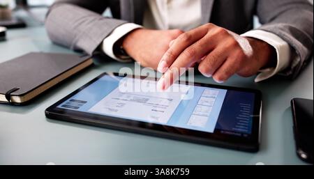 Young accountant calculating expenses, preparing electronic invoice on computer software. Stock Photo