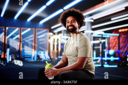 Young African American athlete taking break, refreshing with water bottle. Stock Photo