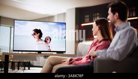 Cozy Night In: Couple Relaxing on Sofa Watching TV Together. Stock Photo