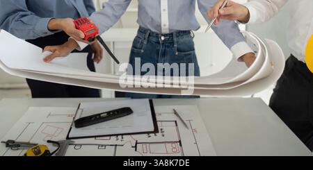 Teamwork and Project Discussion. Professionals examining detailed construction plans while focused on efficient building design. Stock Photo