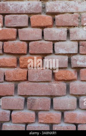 unmaintained old brick wall made of orange old bricks with completely chipped plaster Stock Photo