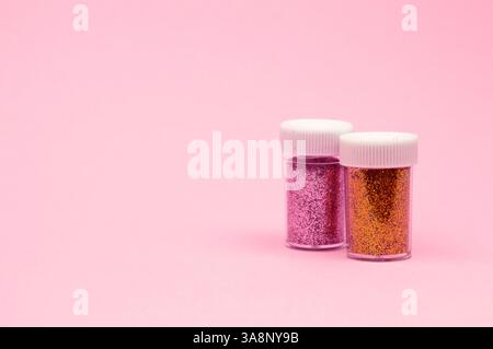 Tiny, sparkling sequins in vivid colors fill small containers, set against a soft pink backdrop in this eye-catching layout. Stock Photo